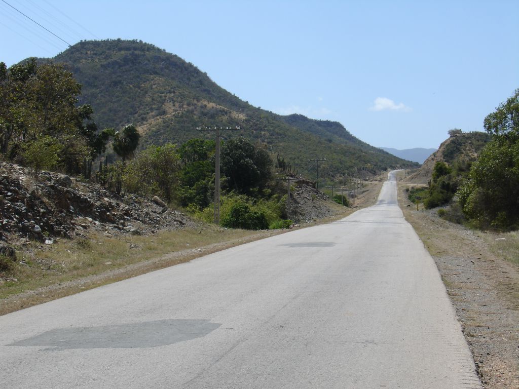 Die Straße führt von der Küste weg durch eine hügelige Landschaft.