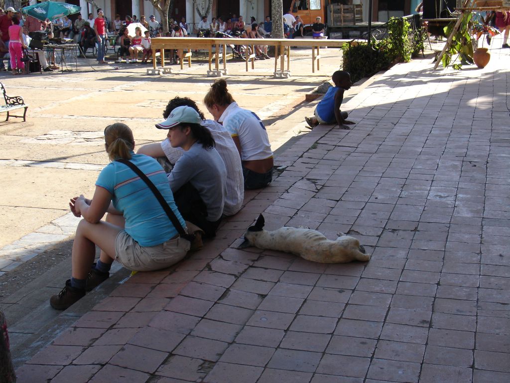 Touristen sitzen im Schatten - und auch ein Hund genießt den Schatten.