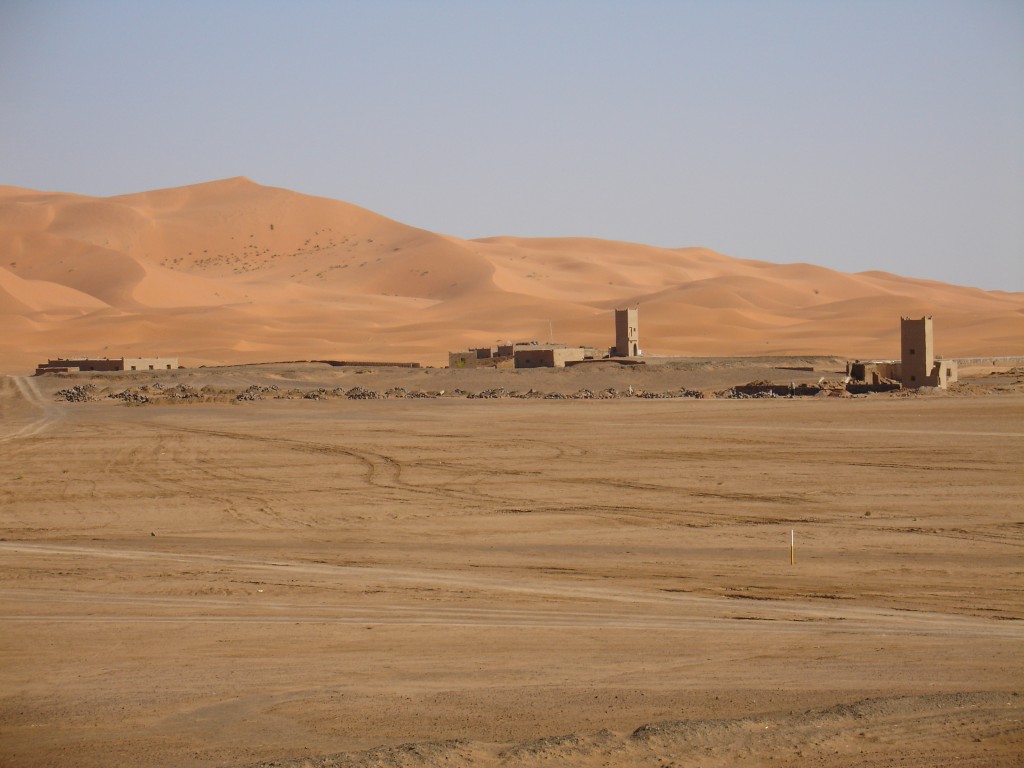 Die Sanddünen des Erg Chebbi kamen langsam näher. In der Wüste tauchten einzelne Häuser auf, meistens Hotels. Bis vor einigen Jahren haben nur wenige Leute in Merzouga gelebt. Durch den Tourismus sind inzwischen viele neue Häuser gebaut worden, zu einem großen Teil Hotels.